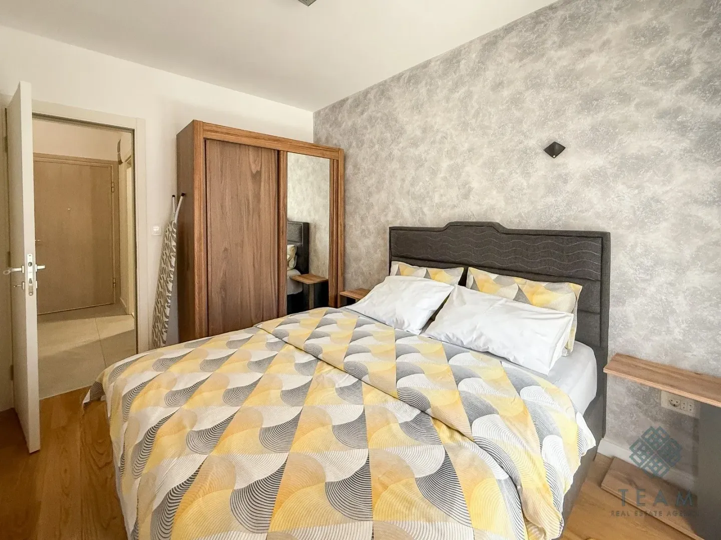 Furnished bedroom with a double bed, wardrobe, and hallway entrance.