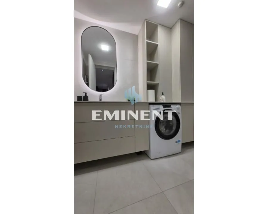 Modernly equipped bathroom with a washbasin, mirror, and washing machine.