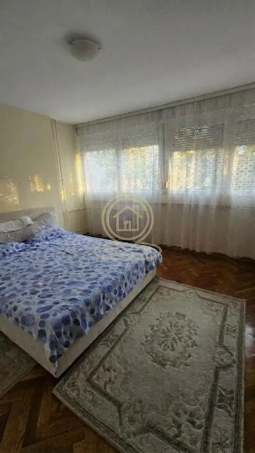 Furnished bedroom with a double bed and curtained windows.