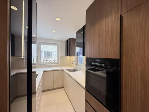 Modern kitchen with built-in appliances and wooden and beige cabinets. - image 7