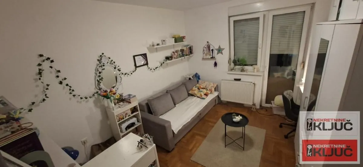 Manja dnevna soba sa kaučem, stočićem i izlazom na terasu.