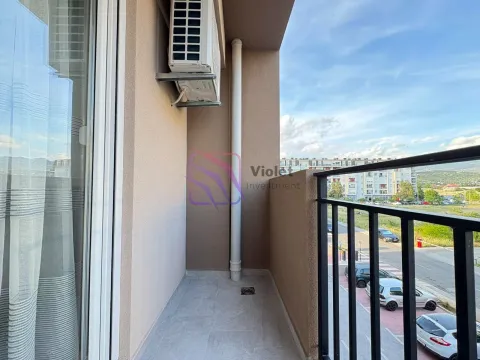 View from the tiled balcony with an air conditioning unit and railing overlooking surrounding buildings and parking. - image 4
