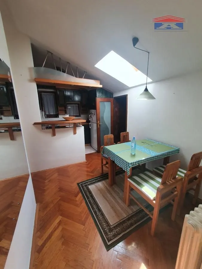 Manja kuhinja sa trpezarijskim stolom i drvenim podom.