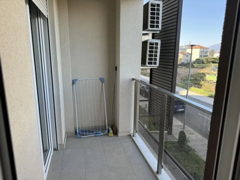 A balcony with a glass railing and an outdoor view.