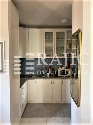 Small kitchen with white cabinets and dark tiles.