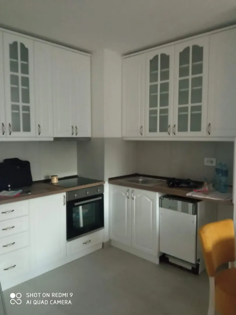 White kitchen with a built-in oven, hob, and sink.