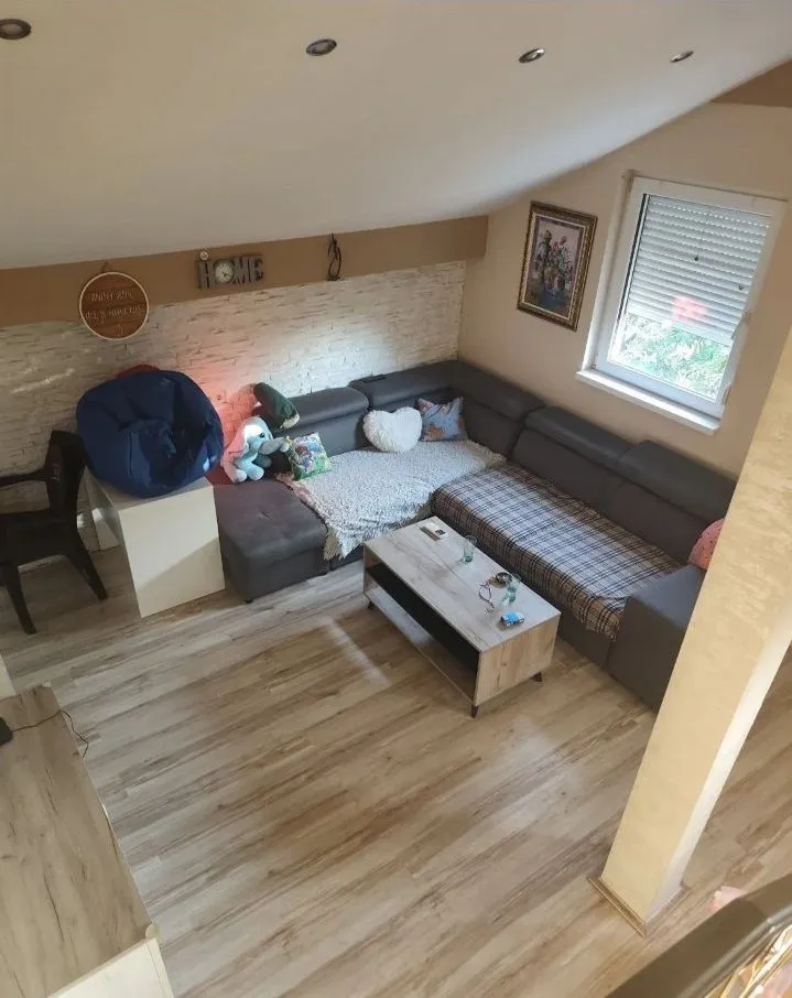 Dnevna soba sa ugaonom garniturom, stočićem i laminatnim podom u potkrovlju.