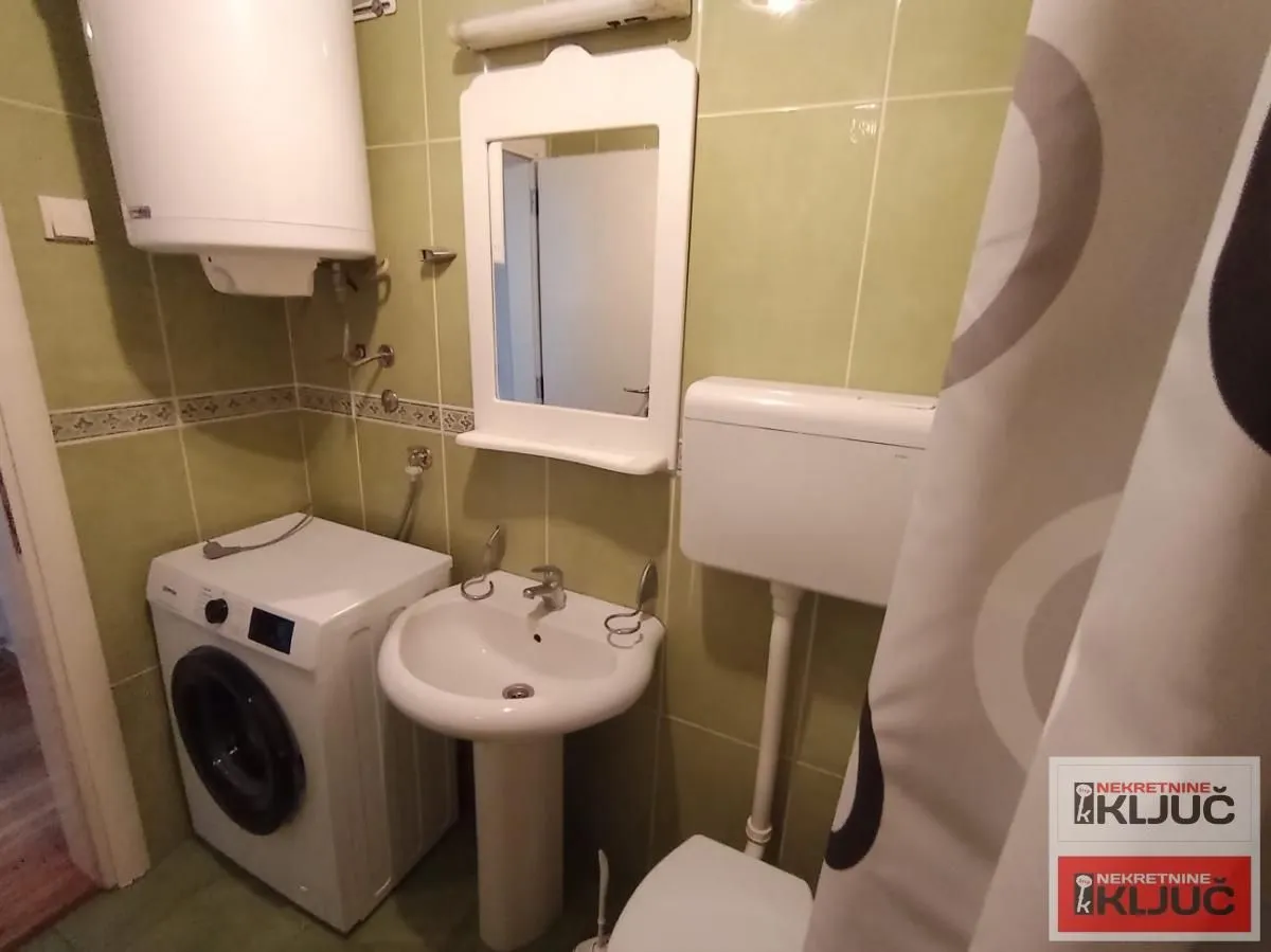 Smaller bathroom with a washbasin, washing machine and a water heater on the wall.