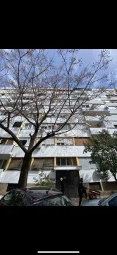 Fasada višespratne stambene zgrade fotografisana odozdo kroz krošnje drveća. - image 3