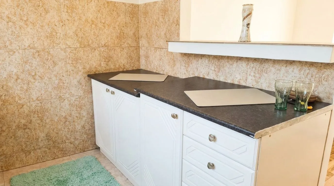 Small part of the kitchen with white cabinets and dark countertop.