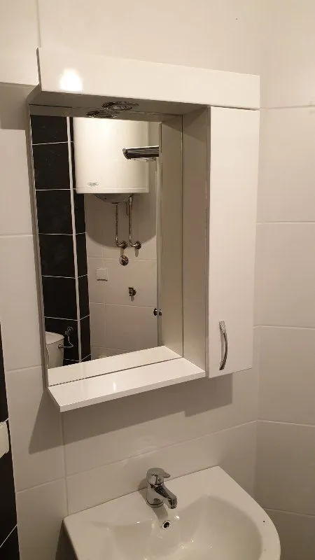 Kupatilo sa belim umivaonikom i ogledalom sa ormarićem.