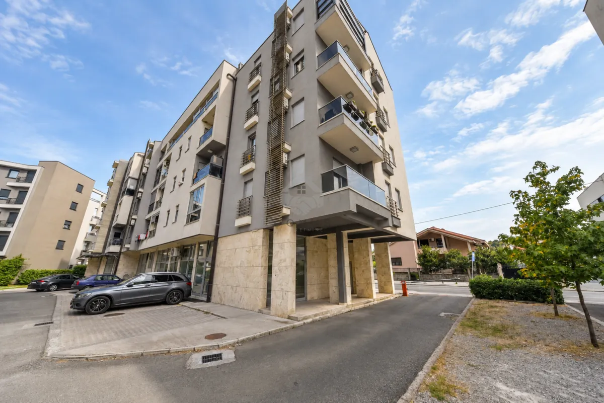 Exterior view of a modern multi-family residential building with parking and balconies.
