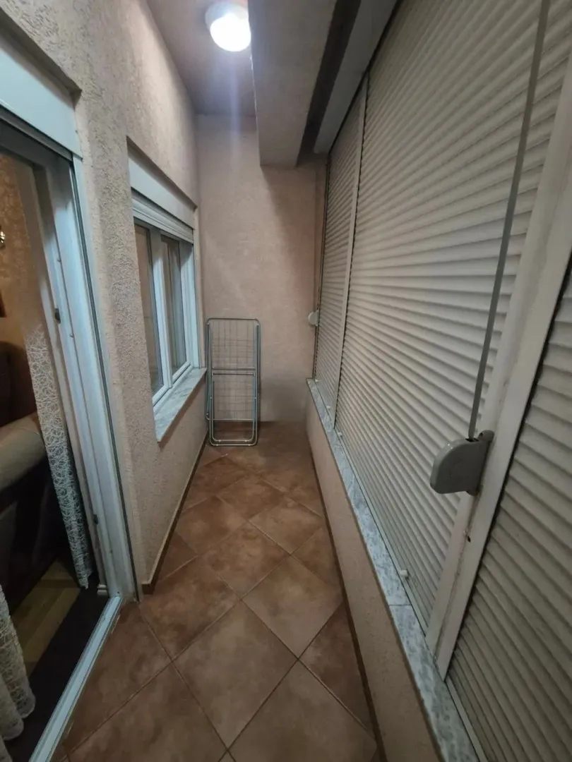Zastakljeni balkon sa keramičkim pločicama na podu.