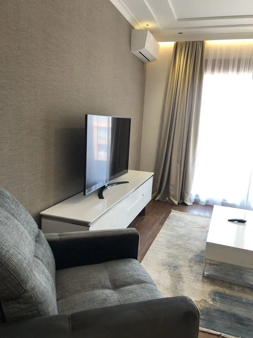 Bright living room featuring a television on a stand and a comfortable armchair.