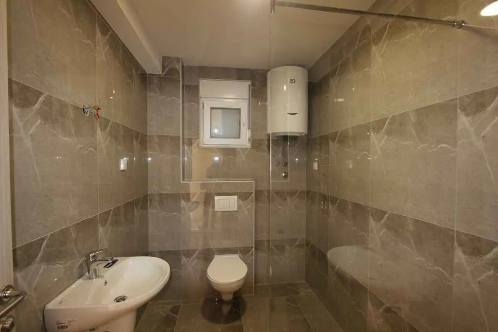 Kupatilo sa sivim pločicama i sanitarijama.