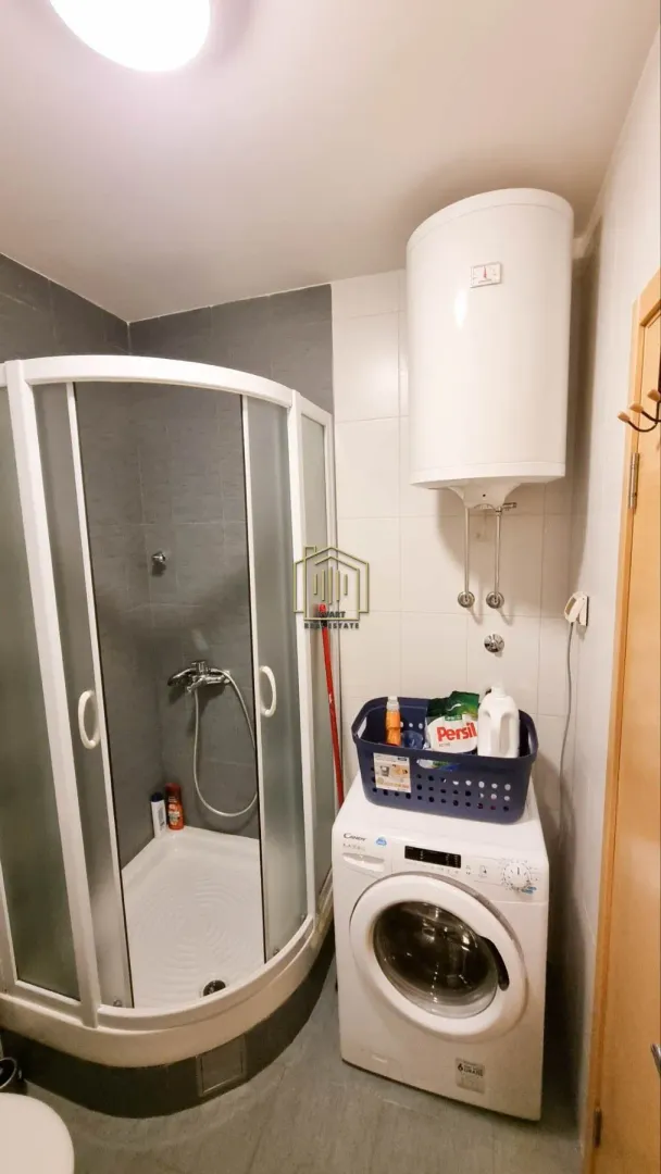 Bathroom with a shower cabin, washing machine, and water heater.