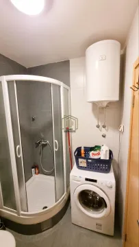 Bathroom with a shower cabin, washing machine, and water heater. - image 5