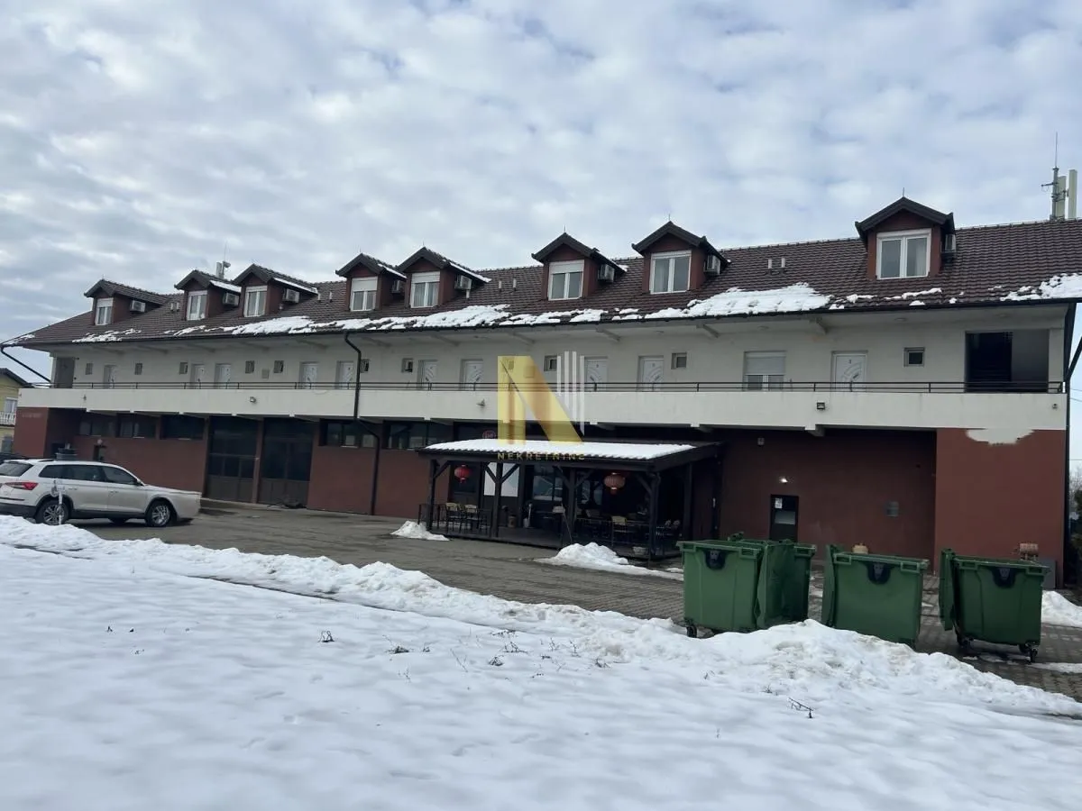 Exterior view of a two-story building with dormer windows and a snow-covered yard.