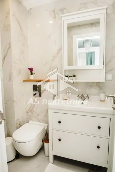 Bathroom equipped with a washbasin, toilet, and a mirror with a cabinet.