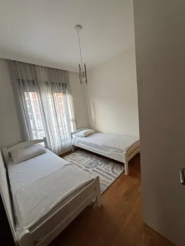 Bedroom with two single beds and a window with curtains. - image 12