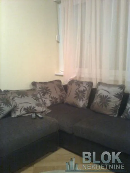 Corner sofa in the living room with cushions and a window in the background.