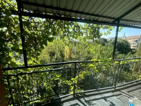 Natkriveni balkon sa pogledom na drveće i okolne zgrade. - image 32