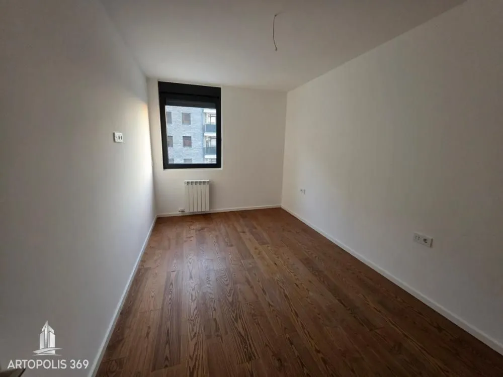 Prazna neuređena soba sa drvenim podom i jednim prozorom.
