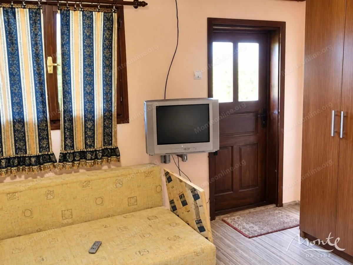 Small living room with a sofa, television and exit through the front door.