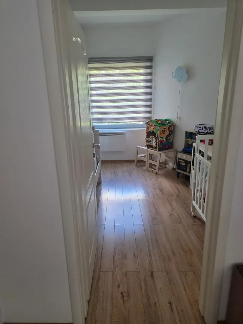 Dječja soba sa krevetcem, igračkama i laminatnim podom.