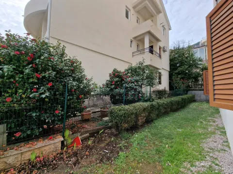 Pogled na dvorište i spoljašnjost zgrade sa uređenim zelenilom i ogradom. - image 5