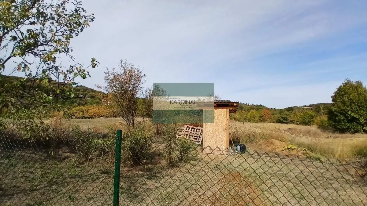 Pogled na ograđeno dvorište i prirodu sa pomoćnim objektom.