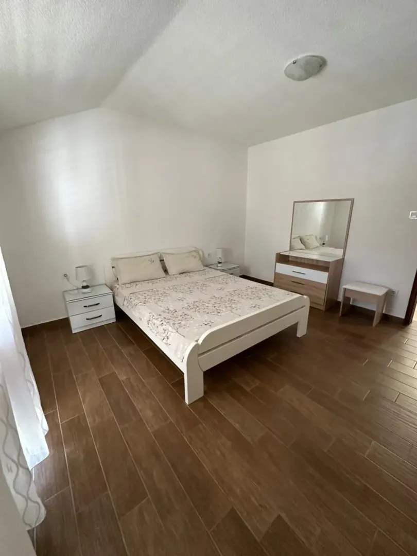 Bright bedroom with a double bed, bedside tables, and a dresser with a mirror.
