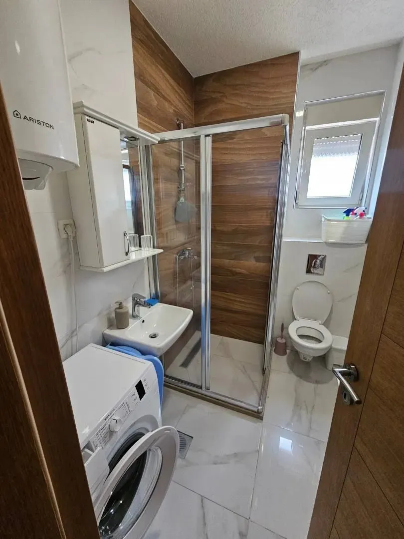 Modernly equipped bathroom with a shower cabin and a washing machine.