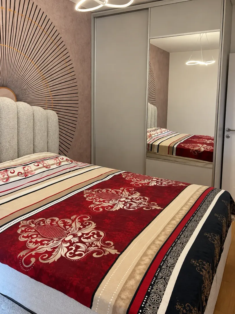 Furnished bedroom with a double bed and a built-in wardrobe with a mirror.