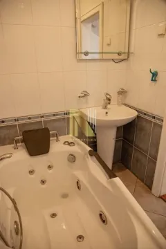 Kupatilo opremljeno hidromasažnom kadom i umivaonikom sa ogledalom. - image 8