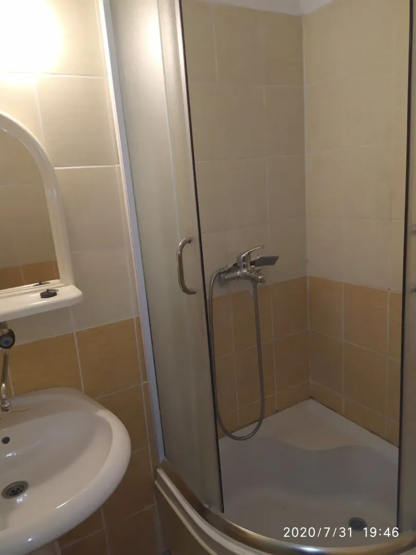 A simple bathroom with a shower cabin and a washbasin.