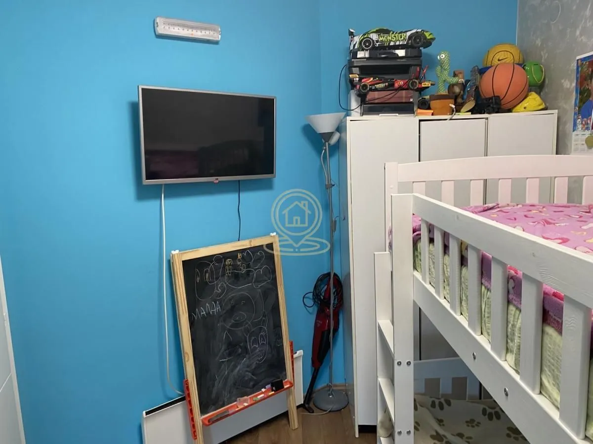 Dečja soba sa krevetom na sprat, plavim zidovima i televizorom.