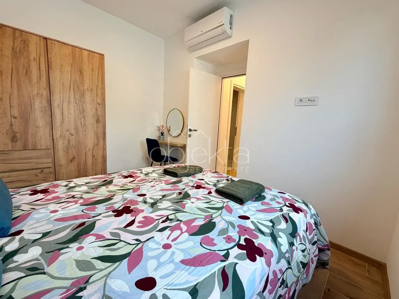 Furnished bedroom with a double bed, wardrobe, and air conditioning unit.