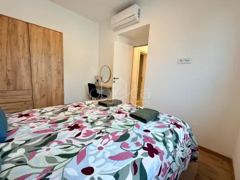 Furnished bedroom with a double bed, wardrobe, and air conditioning unit. - image 11