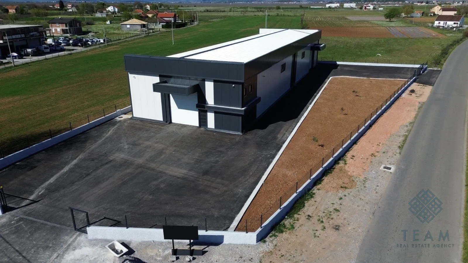 Aerial view of the newly built commercial building with a yard and parking area.