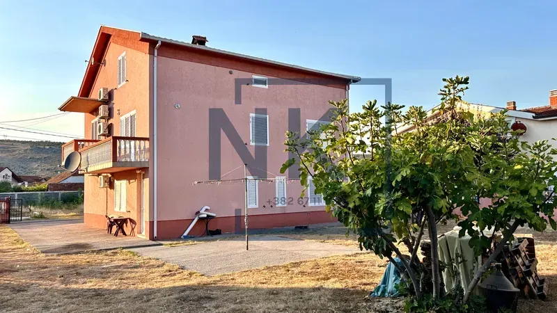 Exterior view of a three-story house with a yard and greenery.