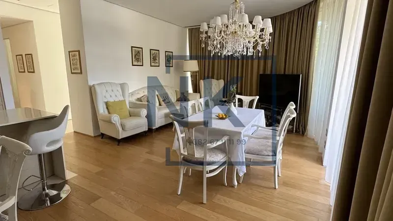 Spacious living room with a dining area, seating set, and a large chandelier.
