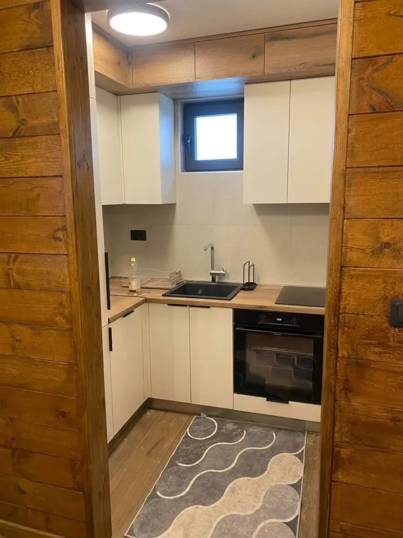 Smaller modern kitchen with white cabinets and wooden details.