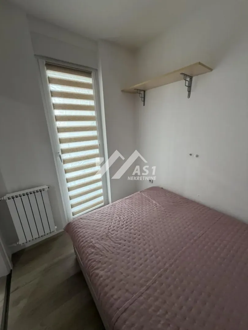 Manja spavaća soba sa krevetom i prozorom.