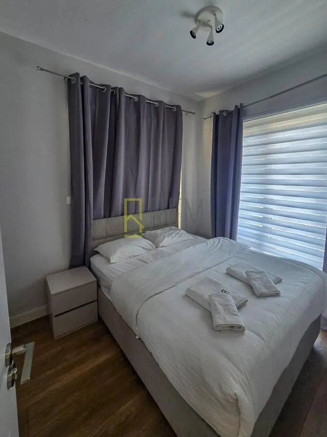 Namještena spavaća soba sa bračnim krevetom i prozorom.