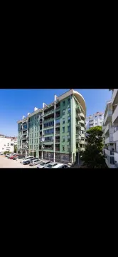 View of the exterior of an apartment building with a green facade and parking. - image 14