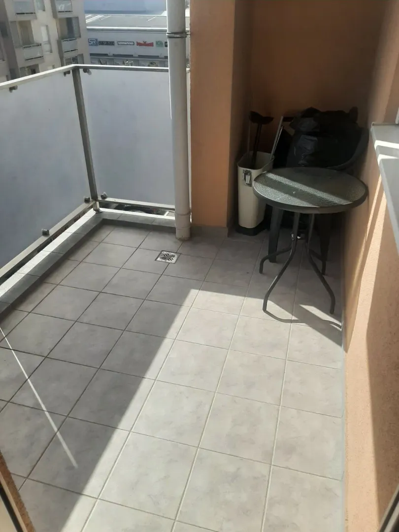 Tiled balcony with a glass railing and a small table.
