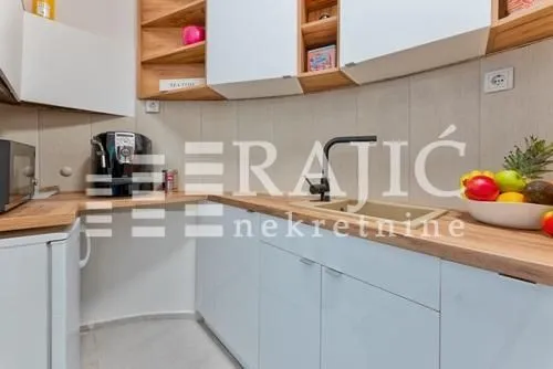 Modern kitchen with white cabinets and a wooden countertop.