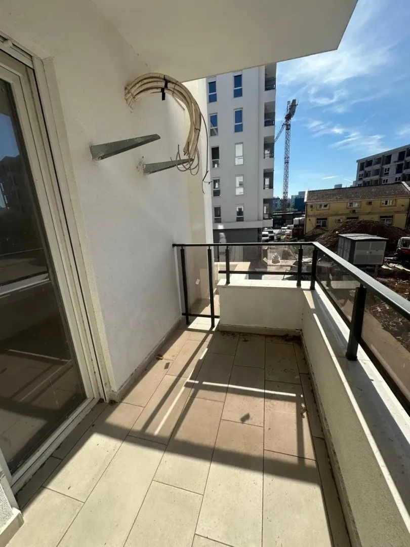 Nenamješten balkon sa pogledom na susjedne zgrade i gradilište.