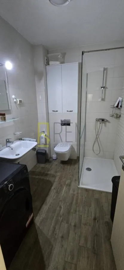 Moderno opremljeno kupatilo sa tuš kabinom i umivaonikom.